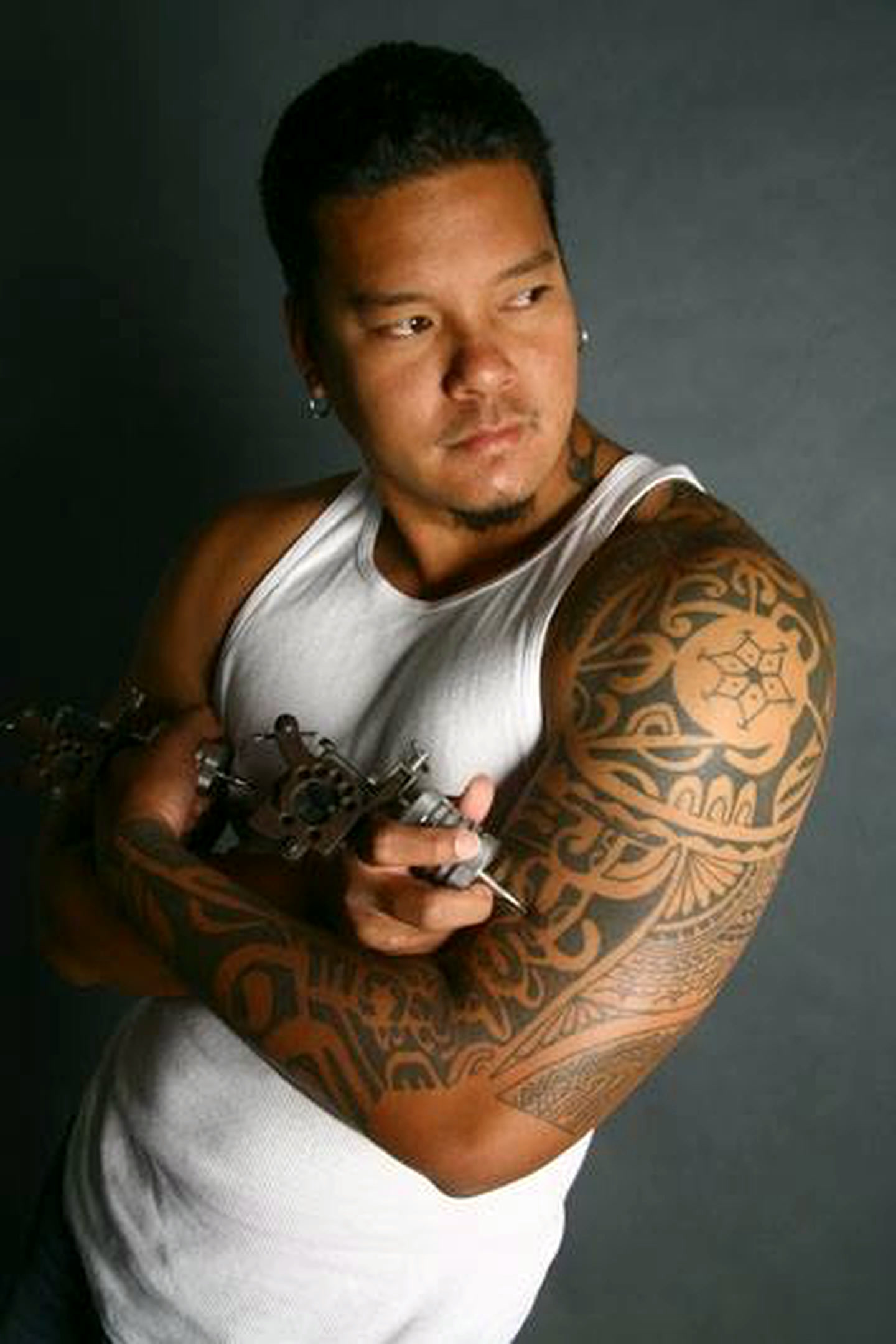 Portrait of David “Boze” Kapoi holding a tattoo machine