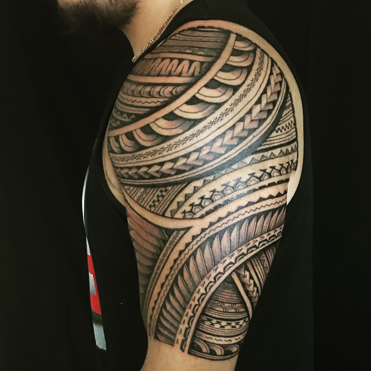 Black and gray geometric tattoo wrapping the upper arm